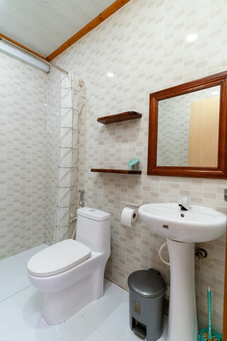 Second bathroom at Maafolhey Han'dhaan tiled in beige, with shower and sink.