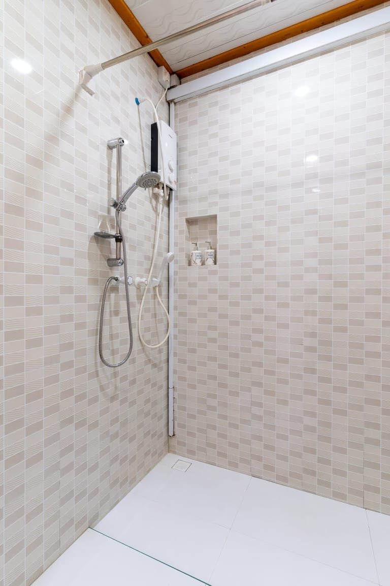 Walk-in shower in the beige-tiled bathroom at Maafolhey Han'dhaan.