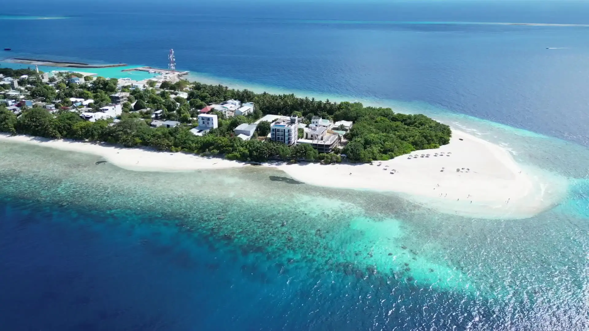 Aerial drone footage of Ukulhas, the local inhabited island where Maafolhey is based, showing the island and its natural beach from above