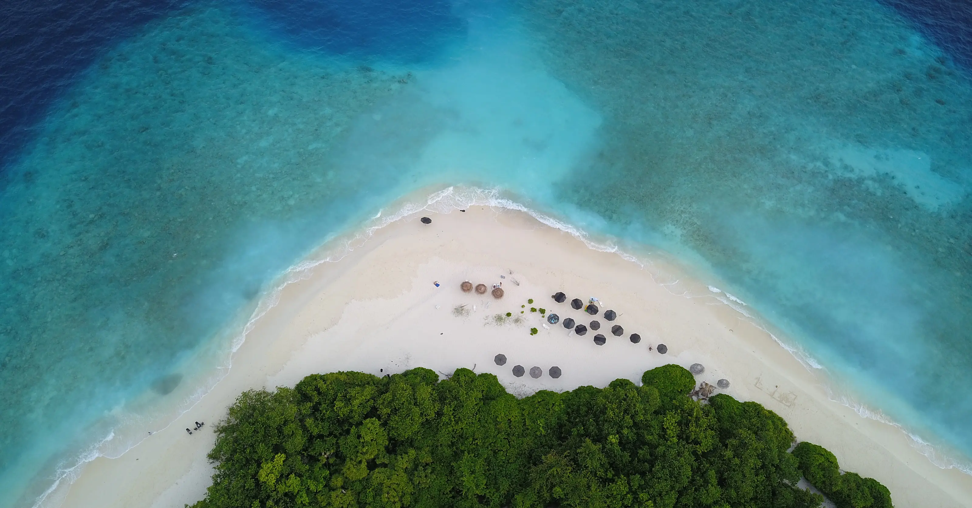 An aerial view of the beach at the tip of Ukulhas, with parasols along the sand