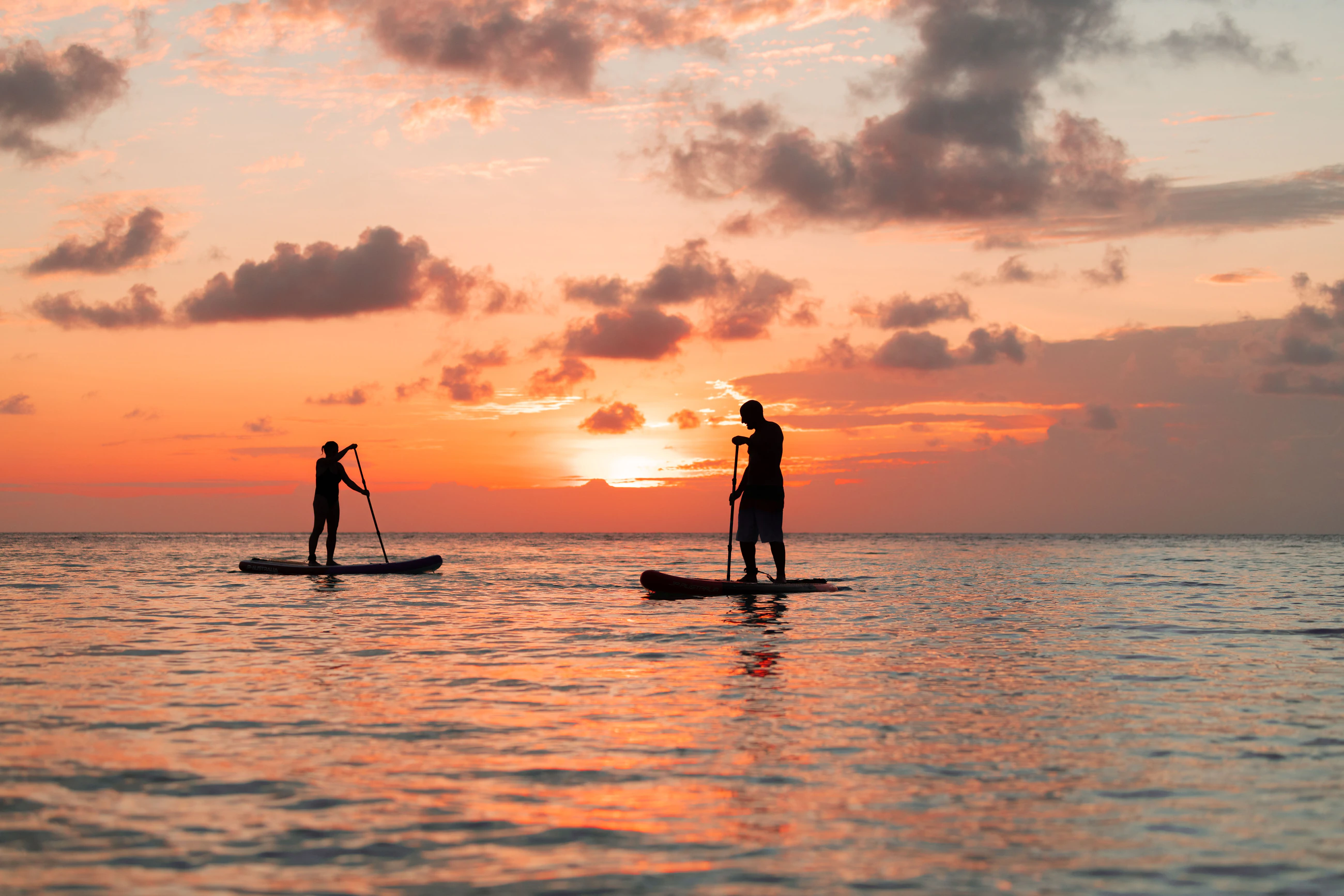 Two paddleboarders on flat water off Ukulhas at sunset